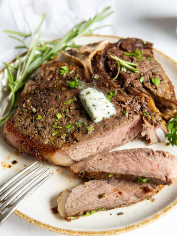 air fryer t bone steak on a white plate, cut into.
