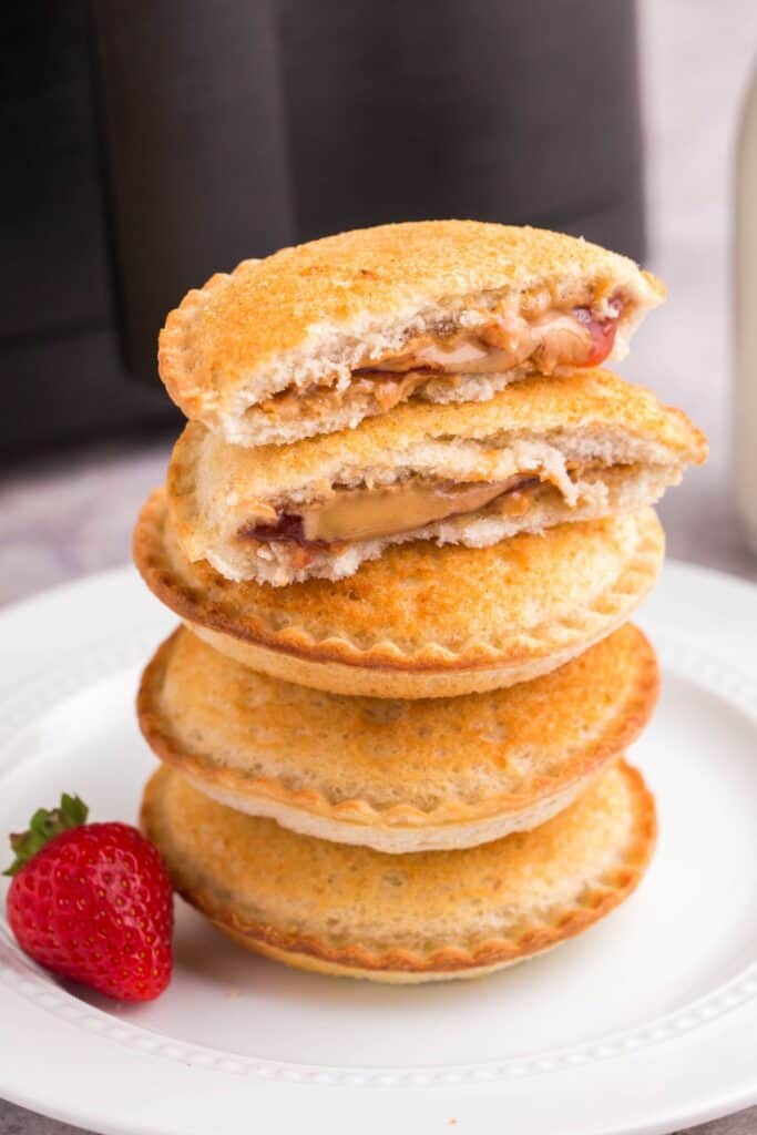 Air fryer Uncrustable stacked on top of more with the top one split in half.