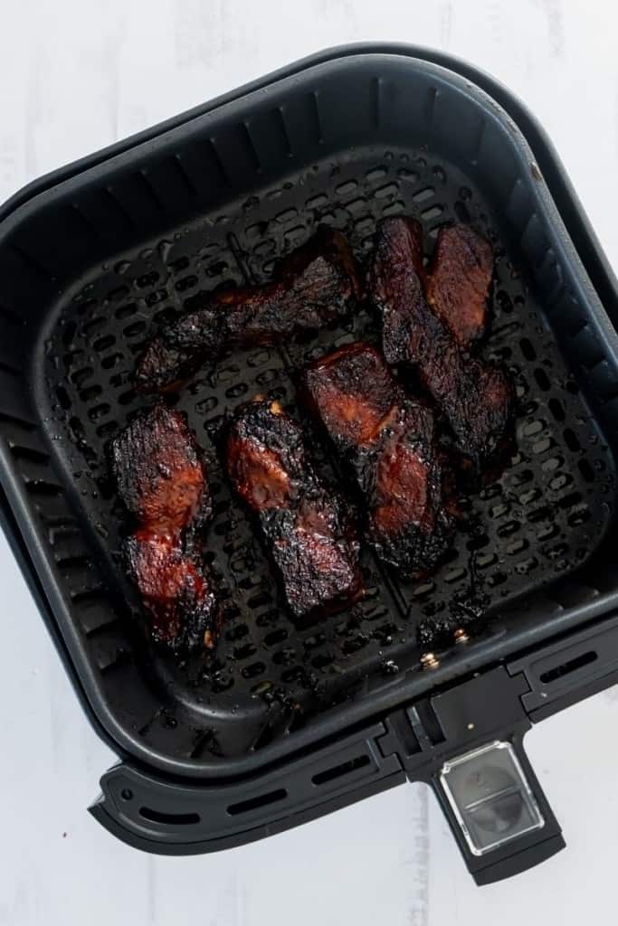 Cooked country style ribs in an air fryer basket.