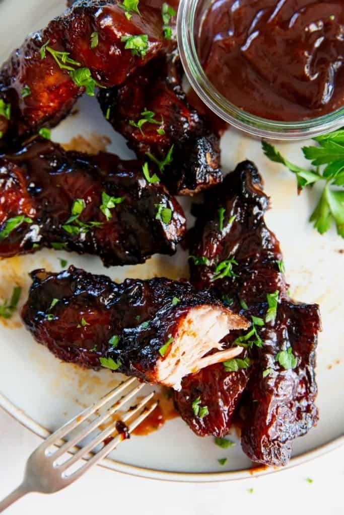 country style ribs cooked in the air fryer on a white plate with one cut open to see in the inside.
