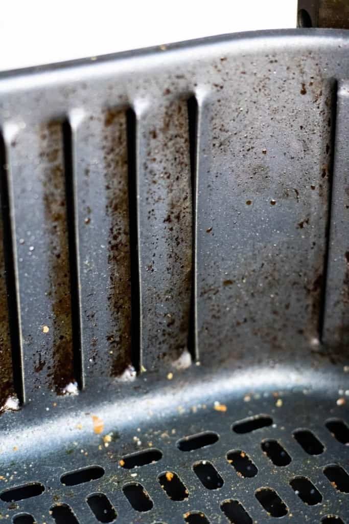 Closeup of baked on grease on air fryer basket