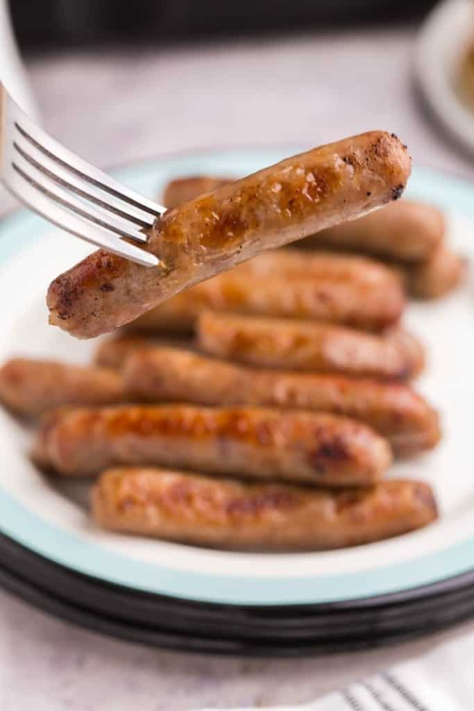 Close up of an air fryer sausage link being held on a fork.