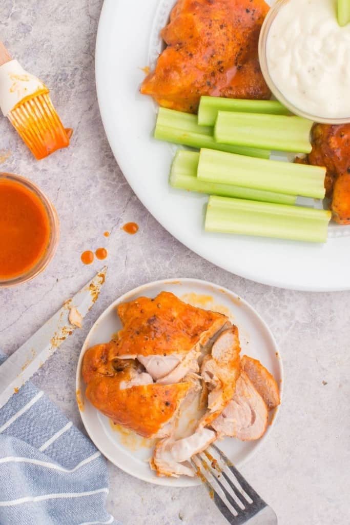 buffalo chicken thighs on plate with celery sticks on another plate