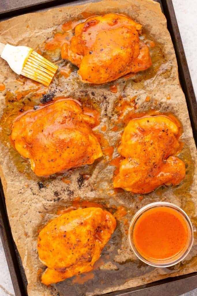 buffalo chicken thighs on cooking pan with parchment