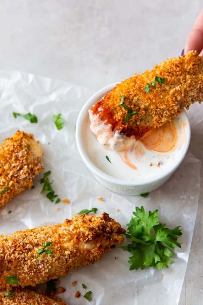 air fryer buffalo chicken tenders being dipped in sauce