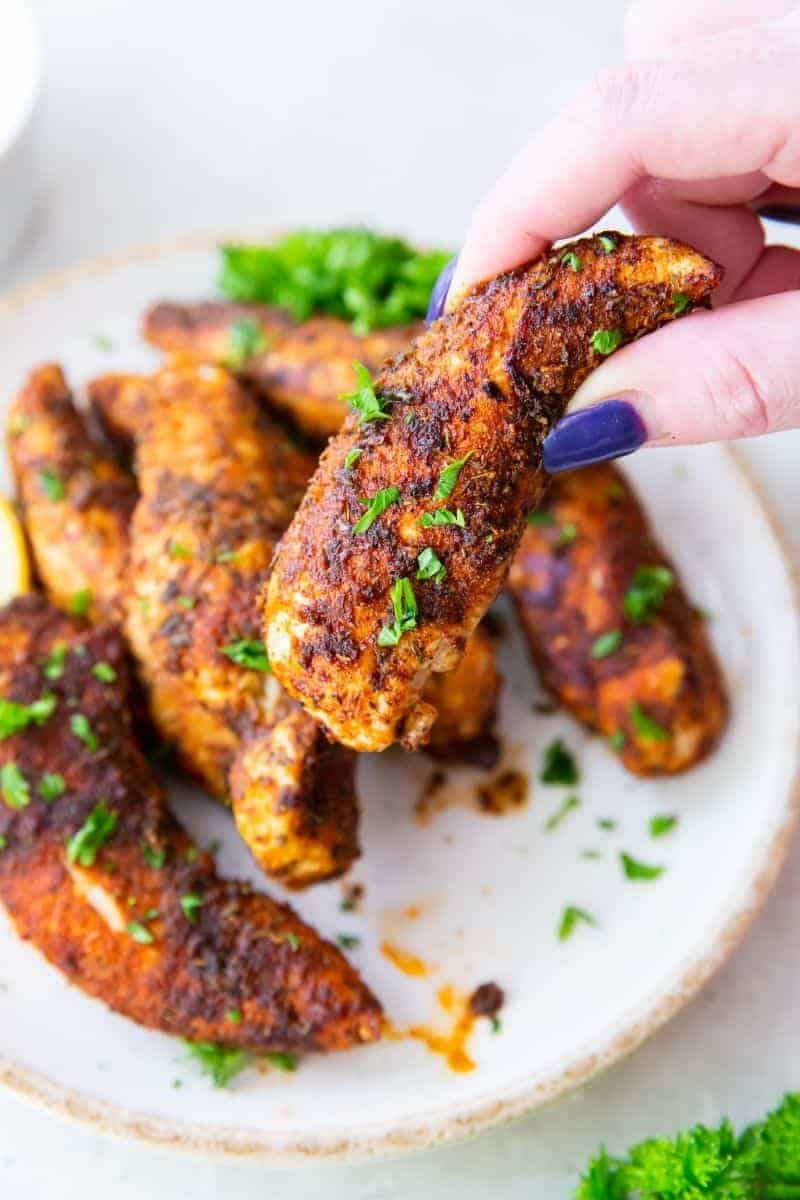 hand grabbing an air fryer chicken tender with no breading
