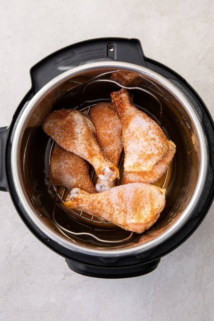 lay seasoned chicken drumsticks on trivet in instant pot