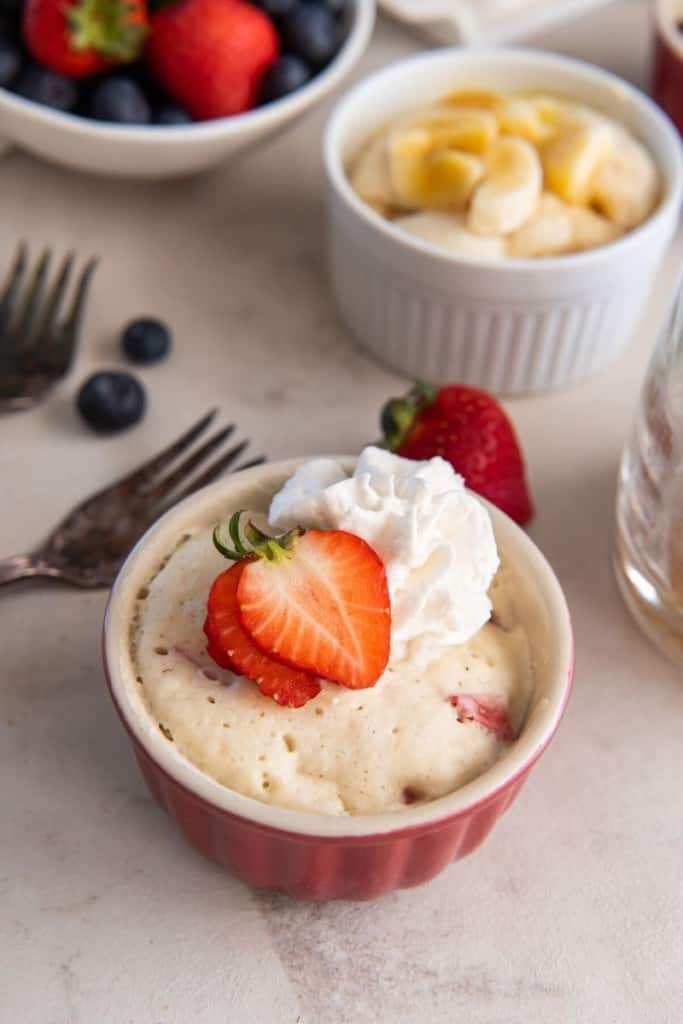 Several pancakes in mugs with different fruit toppings