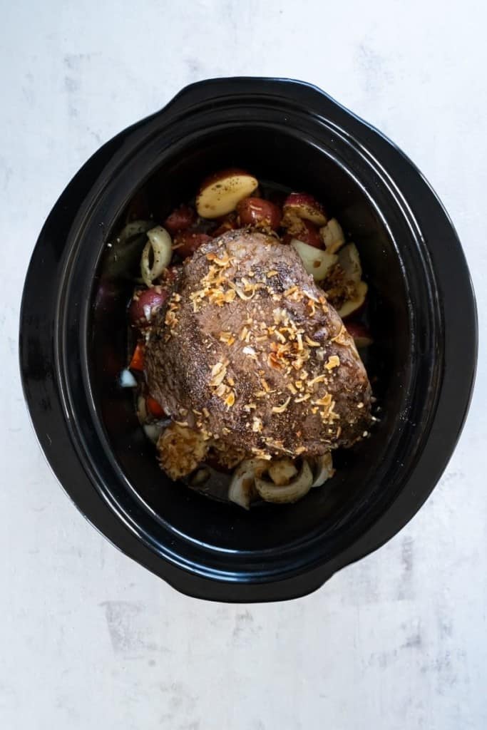 place seasoned tri tip roast on top of vegetables in slow cooker
