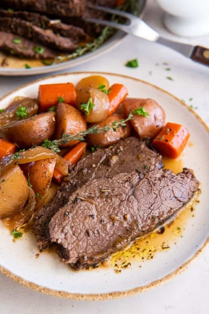 serving plate with slices of crock pot tri tip and vegetables