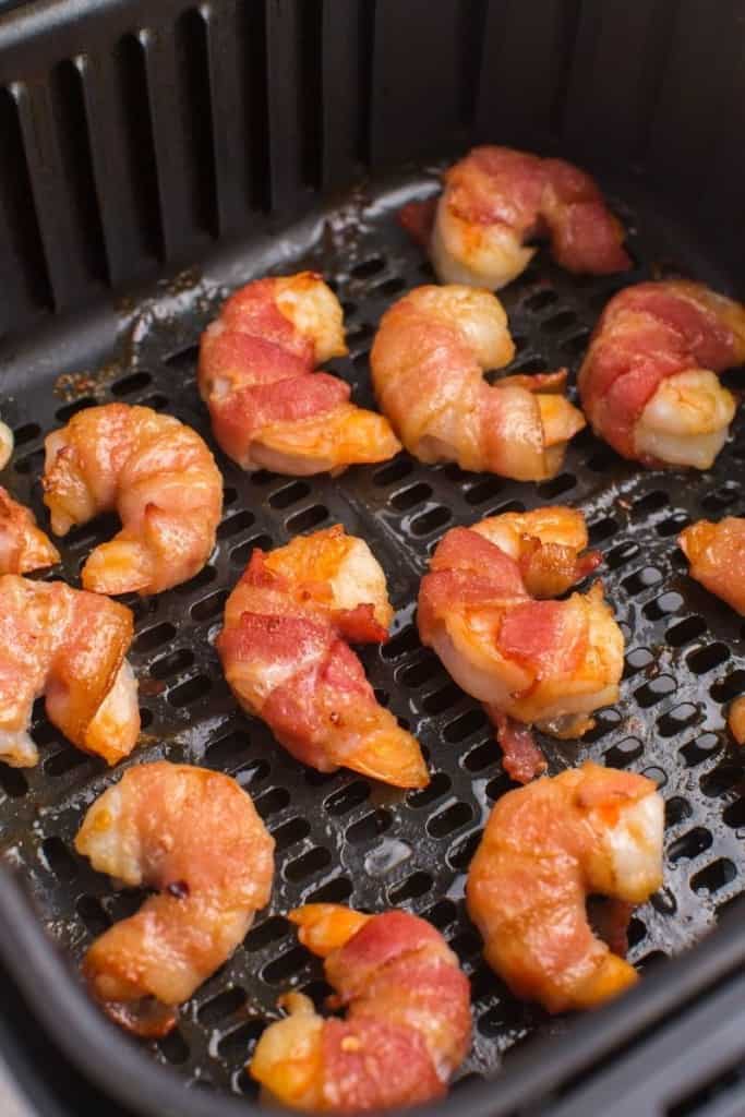flip bacon-wrapped shrimp, add more glaze, and cook longer
