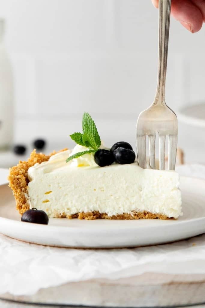 slice of no-bake cheesecake with fork cutting into it