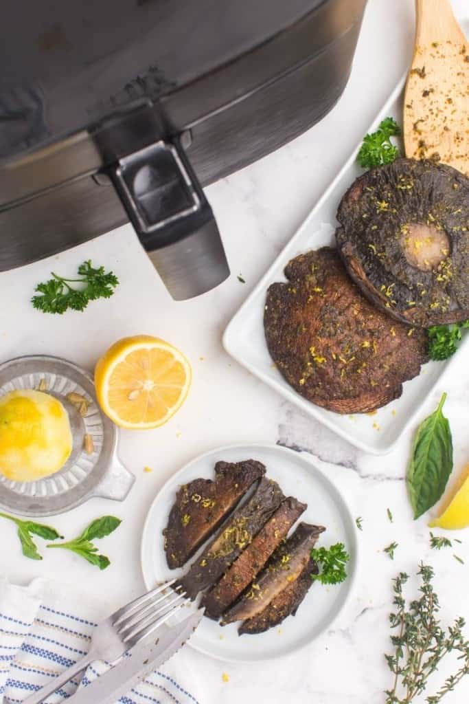 portobello mushrooms with lemon wedges next to air fryer