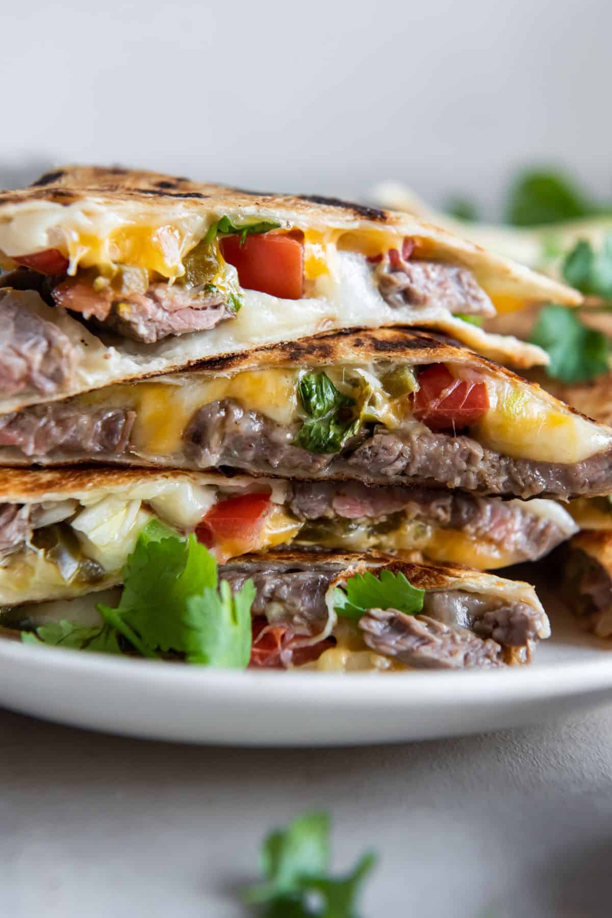 Quesadilla slices stacked on top of each other from a side view to see the carne asada and other ingredients inside.