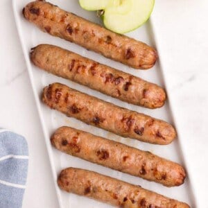 air fryer chicken sausages lined up on white plate