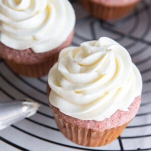 Cream cheese frosting piped on top of strawberry cupcakes.