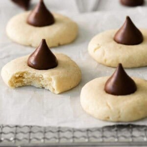 Several sugar cookies topped with hershey kisses on parchment paper
