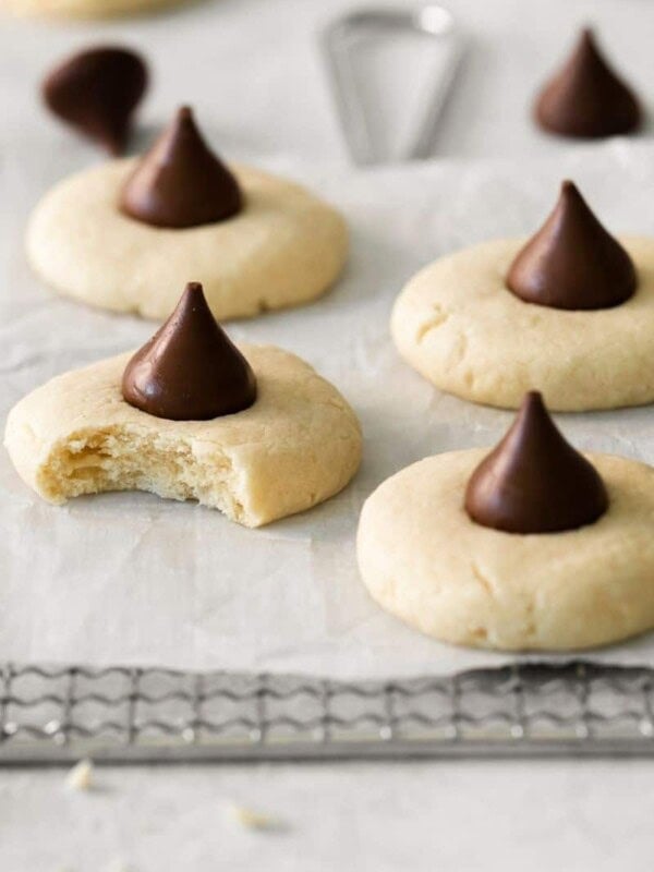 Several sugar cookies topped with hershey kisses on parchment paper