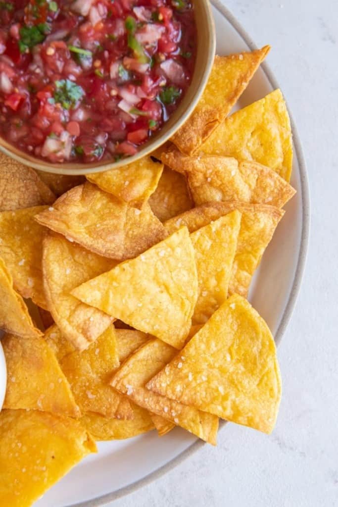 Air Fryer tortilla chips on a plate with a bowl of salsa