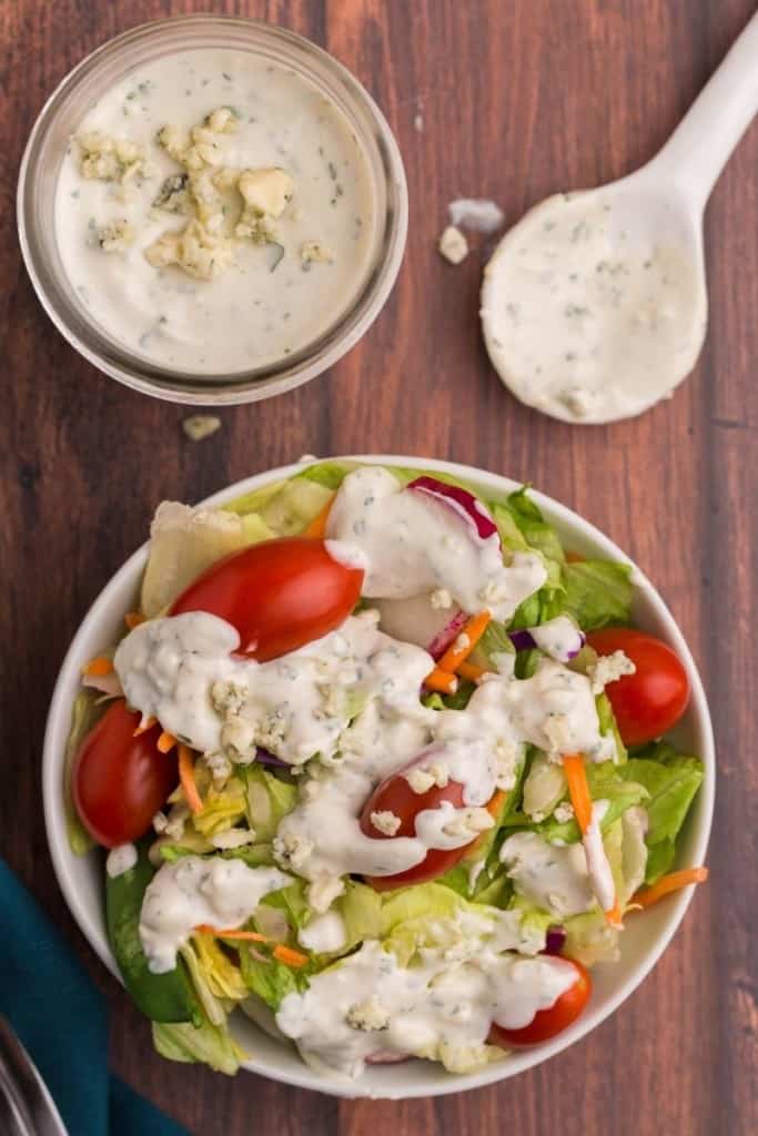 bowl with salad drizzled in blue cheese dressing and jar with dressing