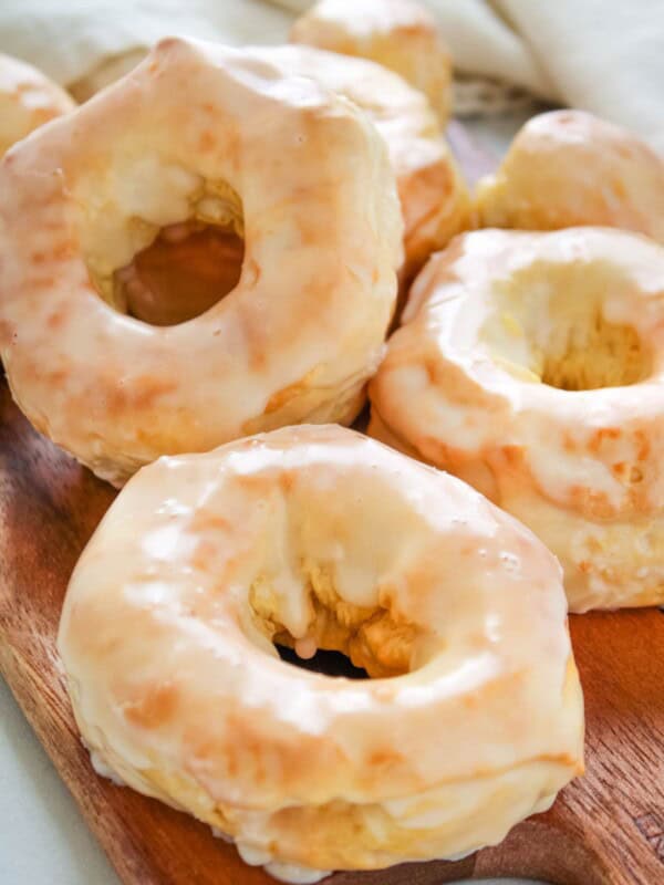 Air fryer donuts covered in glaze on a wooden serving board.