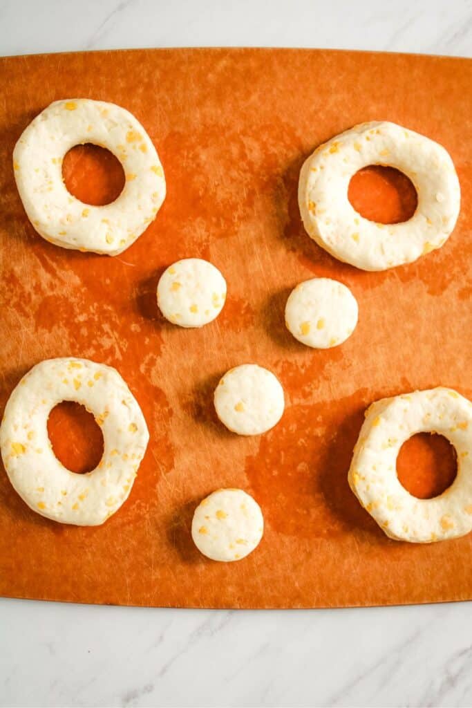 Raw Grands rolls being cut into donuts to air fry.