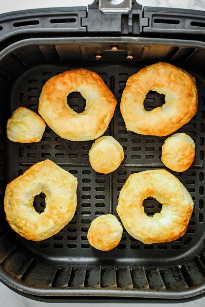 Cooked donuts in the air fryer basket.