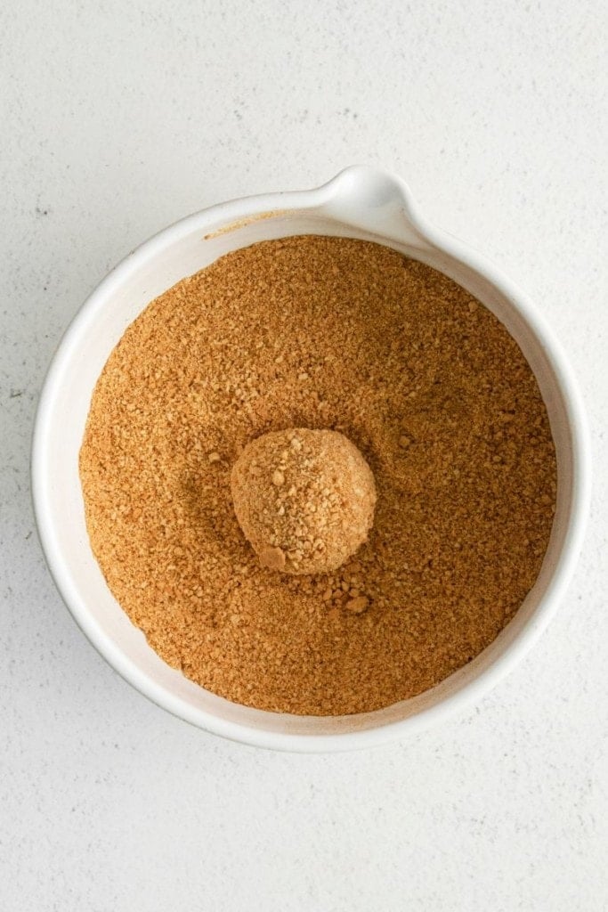 rolling pumpkin cookie balls into pumpkin spice mixture