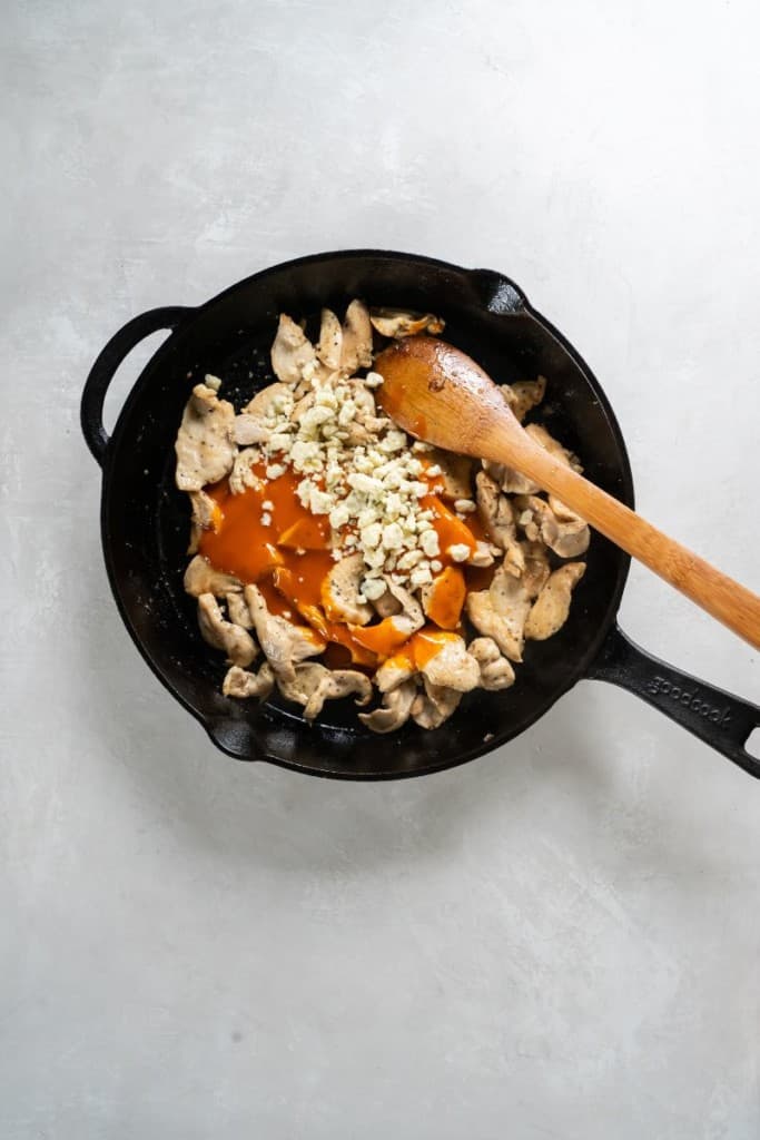 adding sauce to cooked chicken