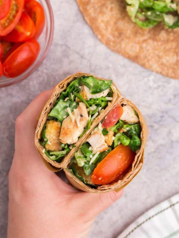 hand holding a grilled chicken caesar wrap