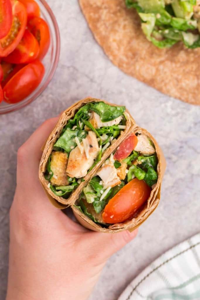 hand holding a grilled chicken caesar wrap