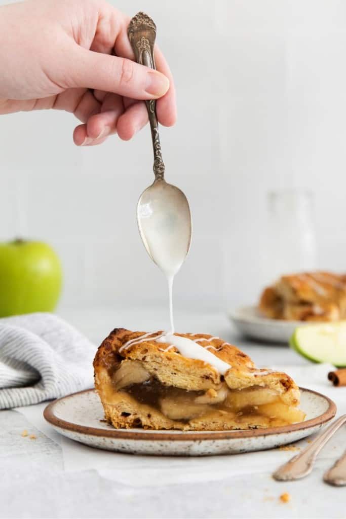 drizzling icing on cinnamon roll apple pie