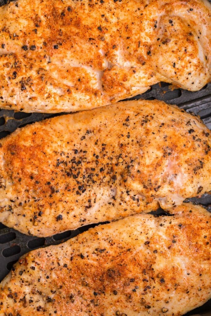 Very close up of the grilled chicken in an air fryer basket.