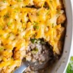 Overhead view of tater tot casserole with green beans with a serving spoon inside and a scoop missing.