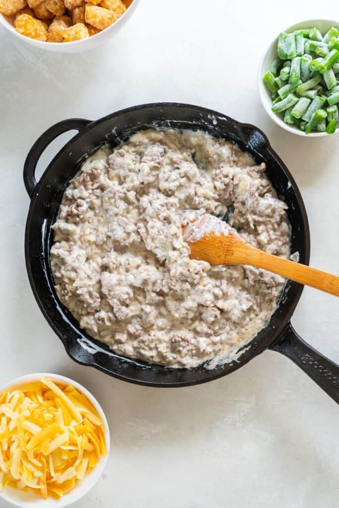 Creamy filling in a cast iron skillet for the tater tot casserole.