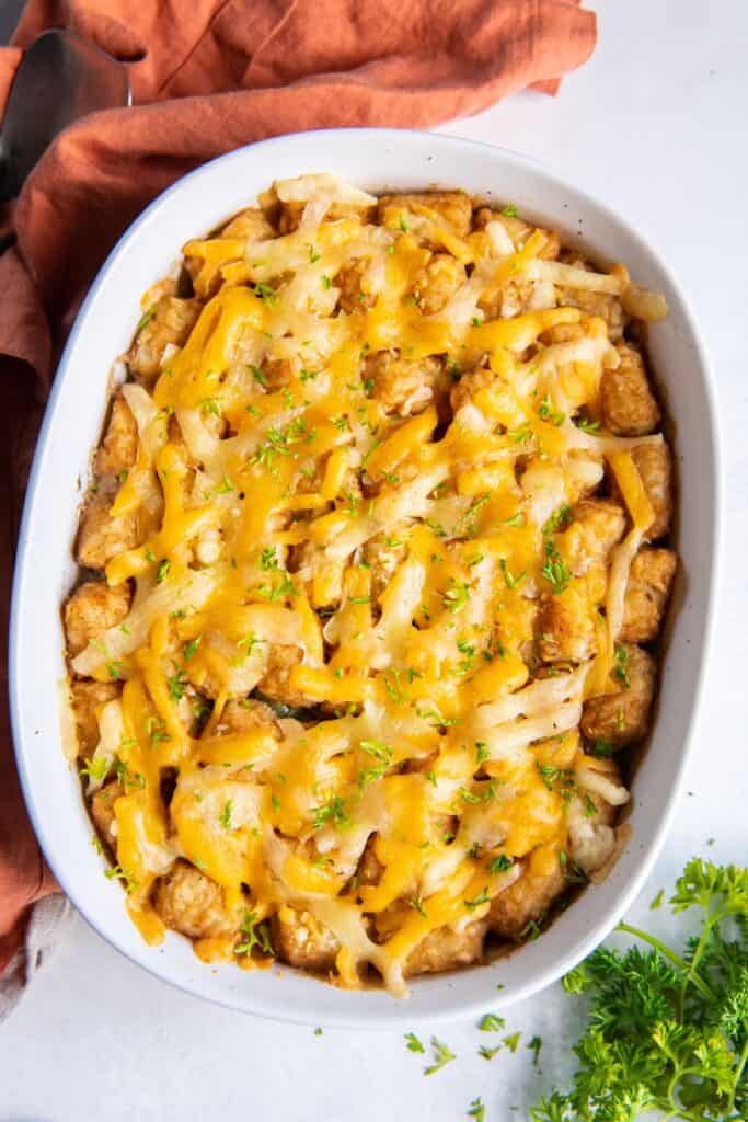 Finished tater tot casserole with green beans in the casserole dish just removed from the oven.