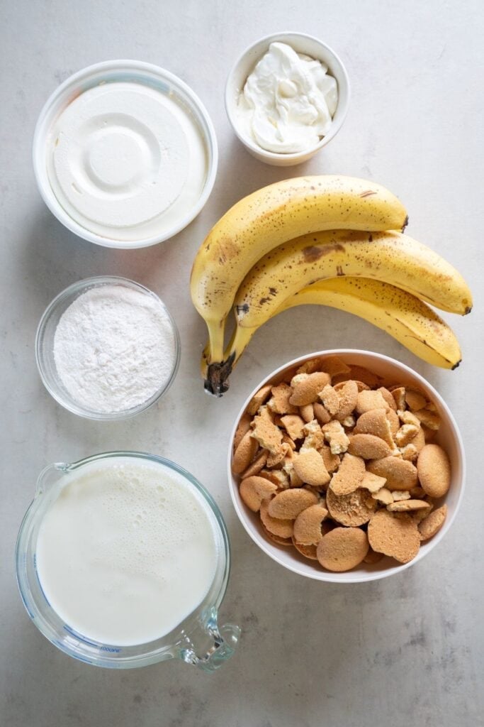 Ingredients needed to make banana pudding with sour cream: instant vanilla pudding mix, milk, sour cream, cool whip, bananas, and vanilla wafers.