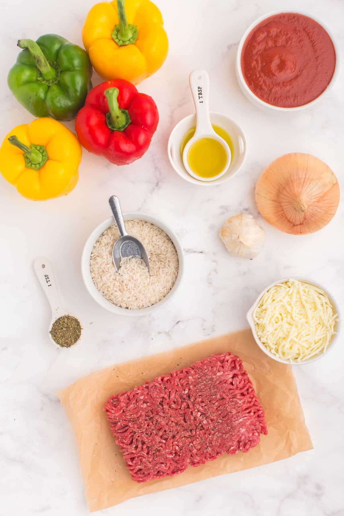 Ingredients needed to make stuffed peppers in the air fryer: bell peppers, ground beef, rice, oil, onion, garlic, tomato sauce, italian seasoning, salt, pepper, and mozzarella cheese.