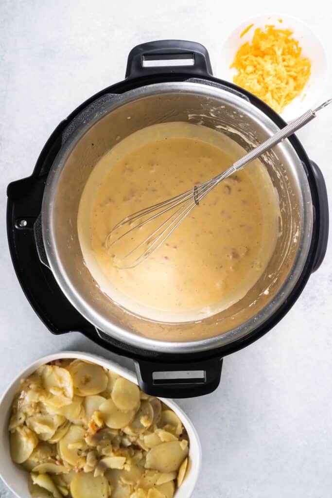 Cheesy sauce in the Instant Pot ready to be poured onto the scalloped potatoes and ham recipe.