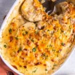 Instant pot scalloped potatoes and ham in a baking dish with a spoon in it.