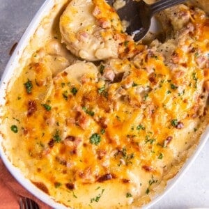 Instant pot scalloped potatoes and ham in a baking dish with a spoon in it.