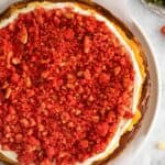 Finished strawberry cheesecake crunch cake recipe that's topped with the frosting and then the crunch topping.