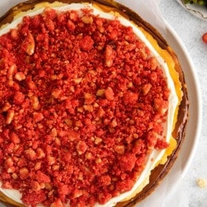 Finished strawberry cheesecake crunch cake recipe that's topped with the frosting and then the crunch topping.