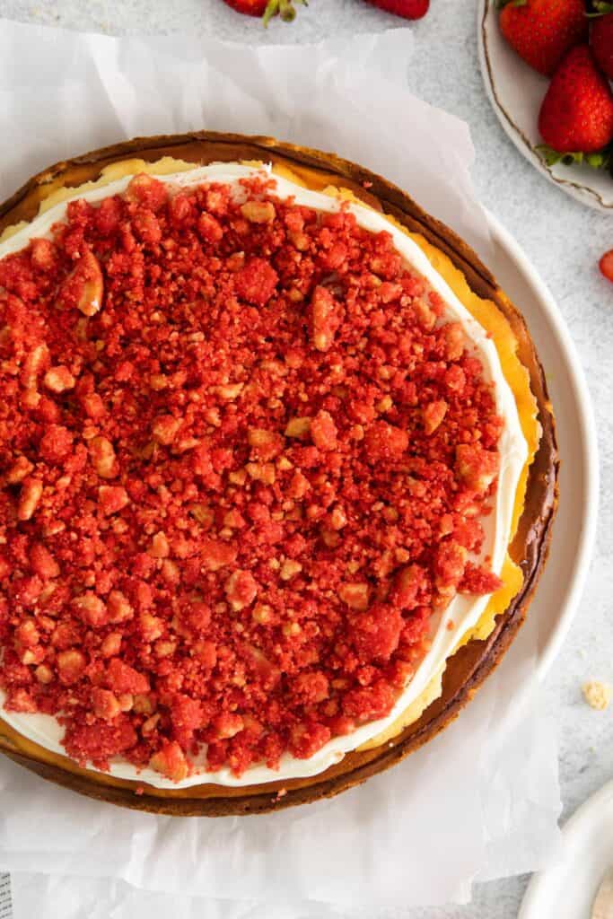 Finished strawberry cheesecake crunch cake recipe that's topped with the frosting and then the crunch topping.