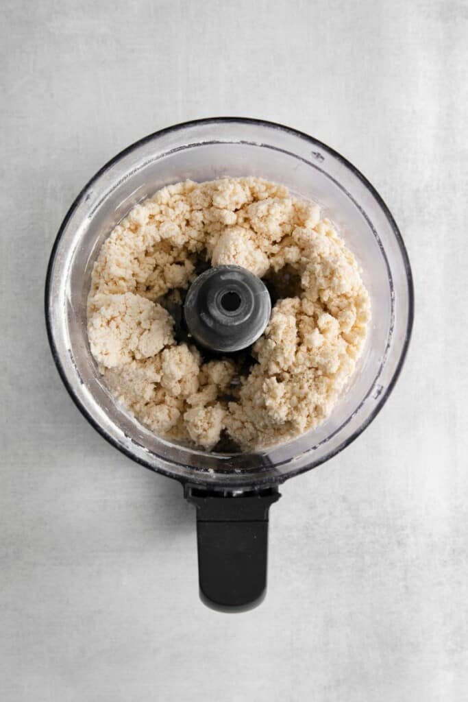 3 ingredient pie crust ingredients in a food processor that has been pulsed to pie dough consistency.