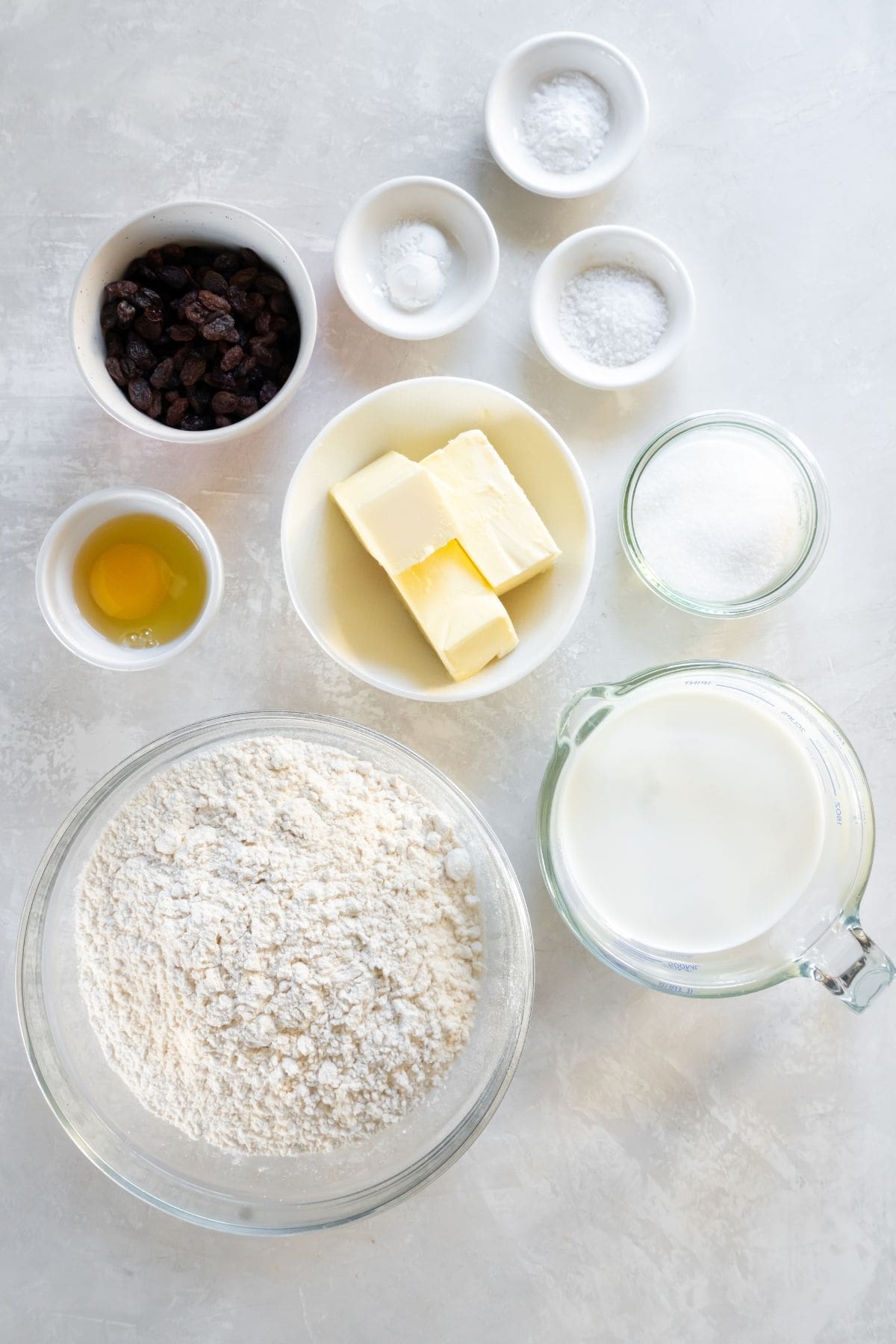 Ingredients needed to make Irish soda bread: butter, flour, sugar, baking powder, baking soda, salt, milk, an egg, and raisins.