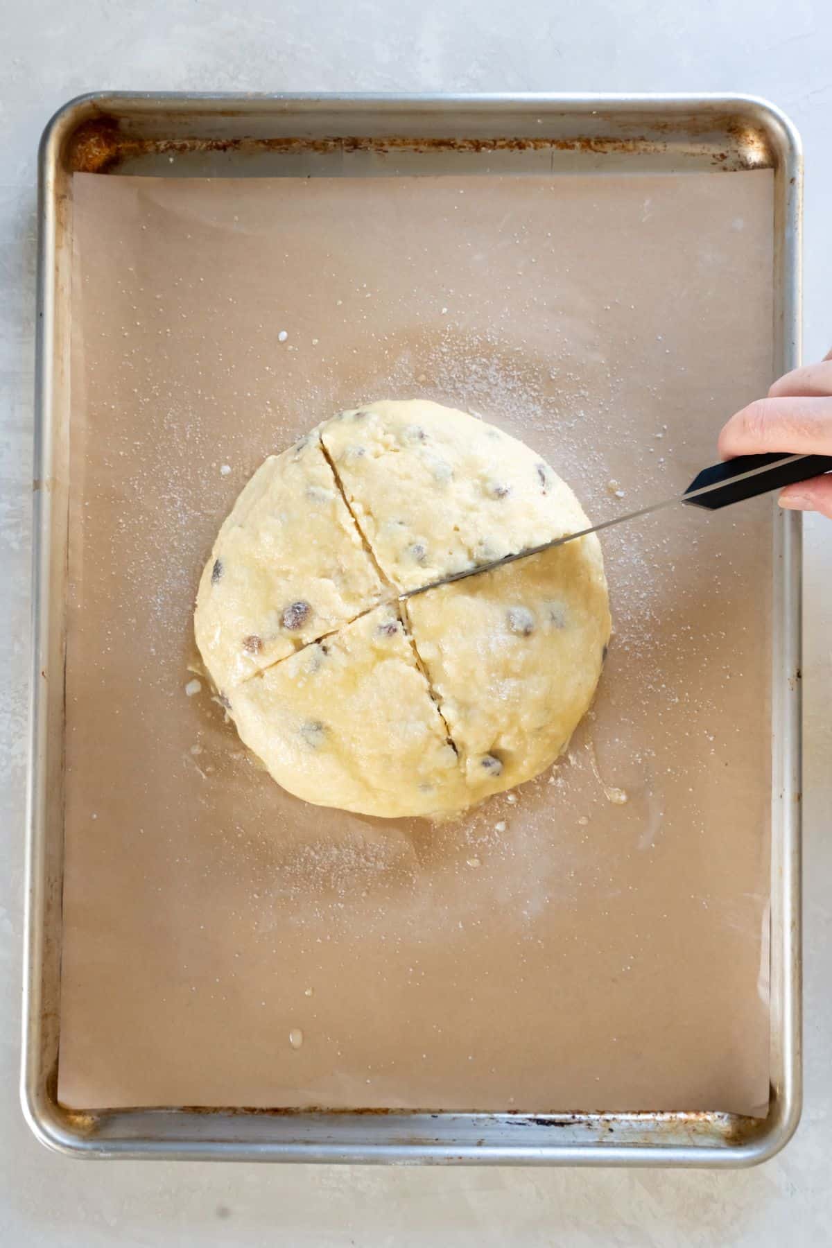 Knife cutting an X on the top of the soda bread.