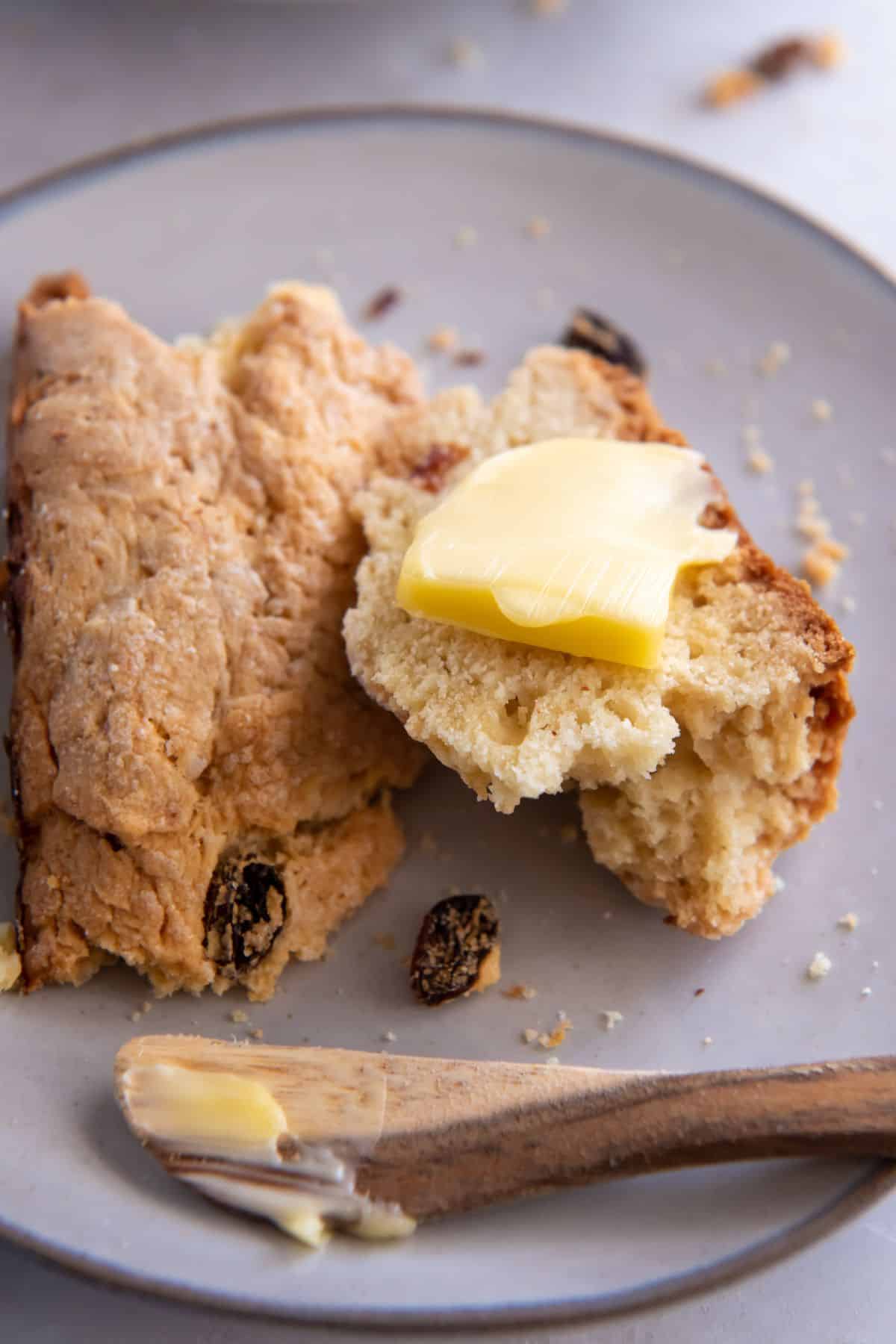 Slice of Irish soda bread with butter on it on a plate.