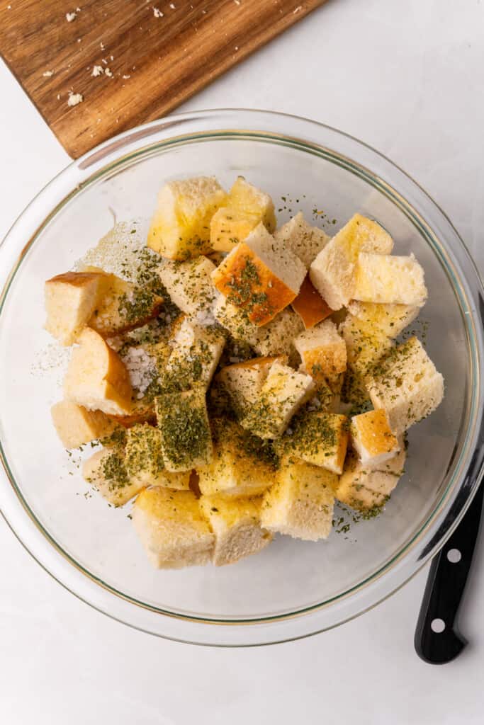 adding seasonings to cubed bread