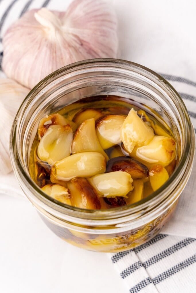 Air fryer roasted garlic cloves in a mason jar submerged in oil to store leftovers.